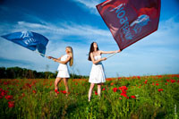 Две девушки в белом на фоне синего неба с красным и синим флагами «Кибербой»