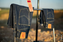 Фото джинсовых шорт, бумажных ярлыков и патчей с логотипами Woodcutter на фоне карьера
