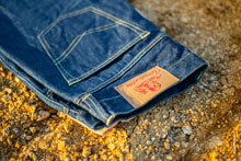 Фото патча с логотипом Woodcutter на поясе синих джинсов на фоне желтого грунта