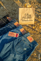 Фото патчей на 4-х джинсовых брюках и бумажного пакета с логотипом Woodcutter на фоне желтого грунта карьера