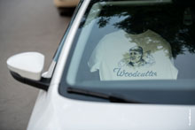 Фото светлой футболки с брендом Woodcutter за лобовым стеклом автомобиля