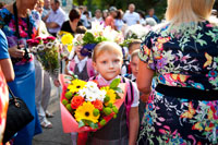 Фото первоклассницы с букетом цветов на фоне паттерна из цветов и цветастых платьев