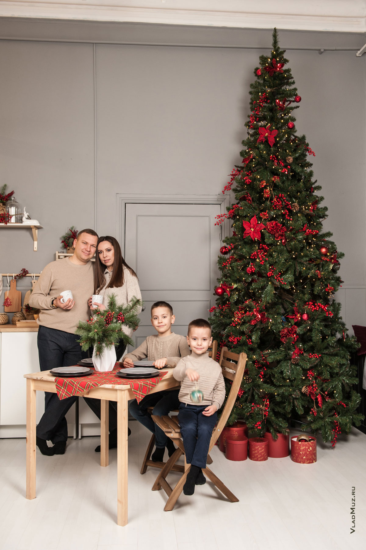 Семейное фото с детьми в студийном интерьере с новогодней елкой