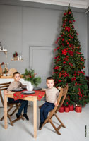 Фото детей за столом в студии на фоне новогодней елки