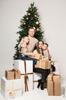Фото семьи с детьми с подарками у новогодней елки в студии на белом фоне