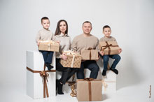 Семейный групповой фотопортрет с детьми, с подарками в руках, в студии на белом фоне