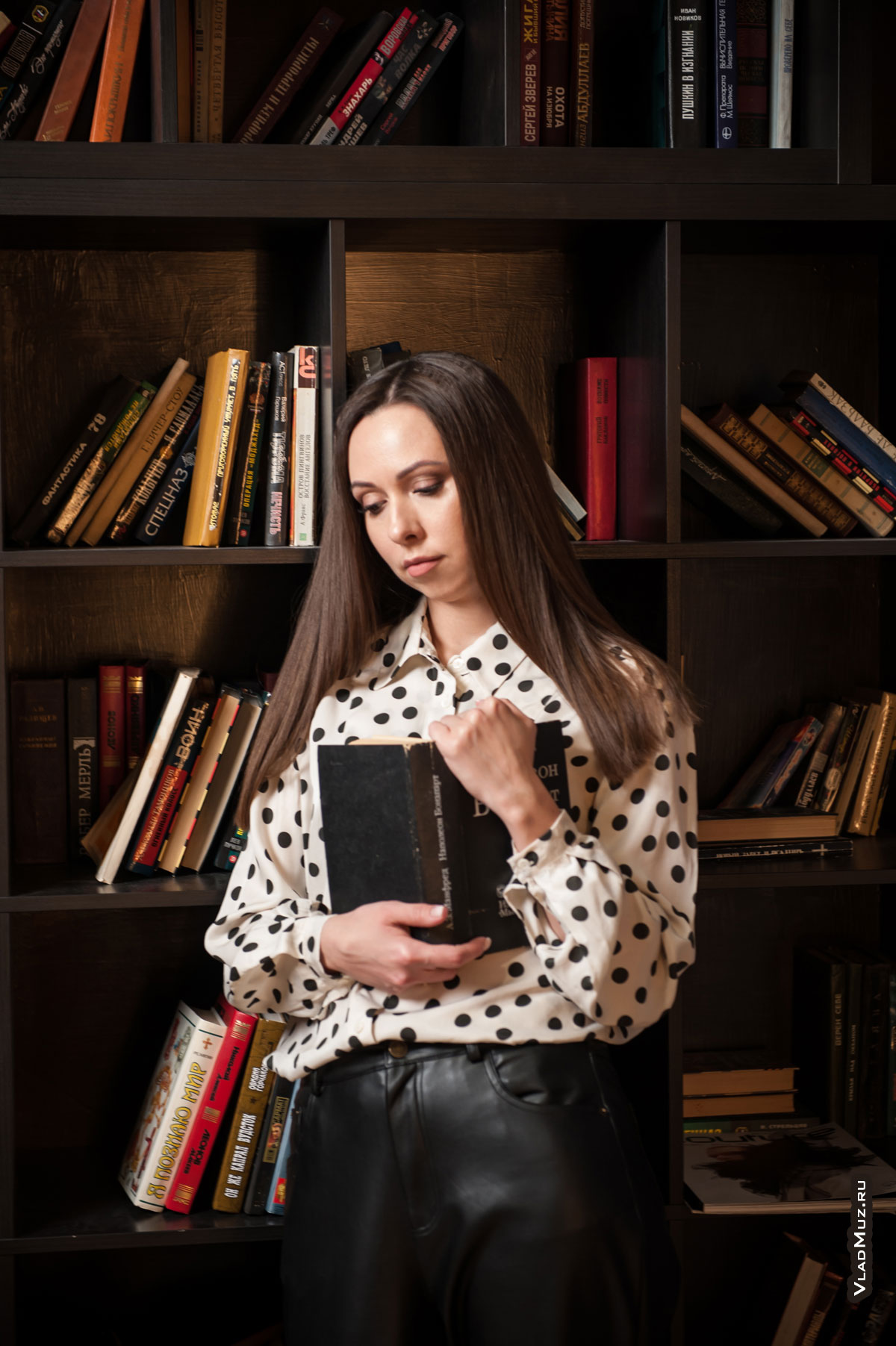 Фото девушки с книгой в руках на фоне книжного шкафа