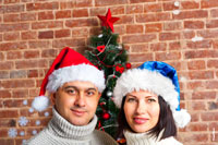 Семейный фотопортрет в новогодних шапках-колпаках на фоне новогодней елки