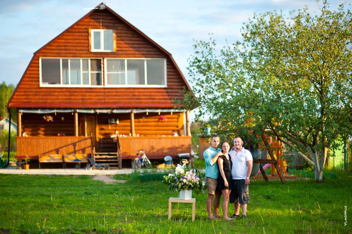 Фото сестры и братьев на лужайке, на фоне деревянного дома