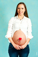 Фотография беременной девушки с улыбкой и с красным сердцем