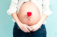 Красное сердце на фоне живота беременной девушки