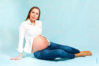 Фото беременной девушки на студийном фоне сидя