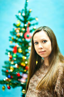 Красивый фотопортрет девушки на фоне новогодней елки в расфокусе