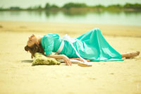 Фото девушки в платье, лежащей на песке, откинув голову назад