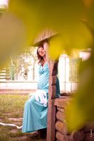 Фото беременной девушки, сидящей у колодца в бирюзовом платье