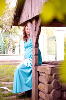 Фото беременной девушки с закрытыми глазами, сидящей у колодца