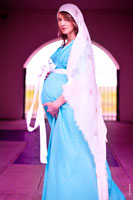 Фото беременной девушки в длинном платке и платье с руками на животе, в библейских мотивах