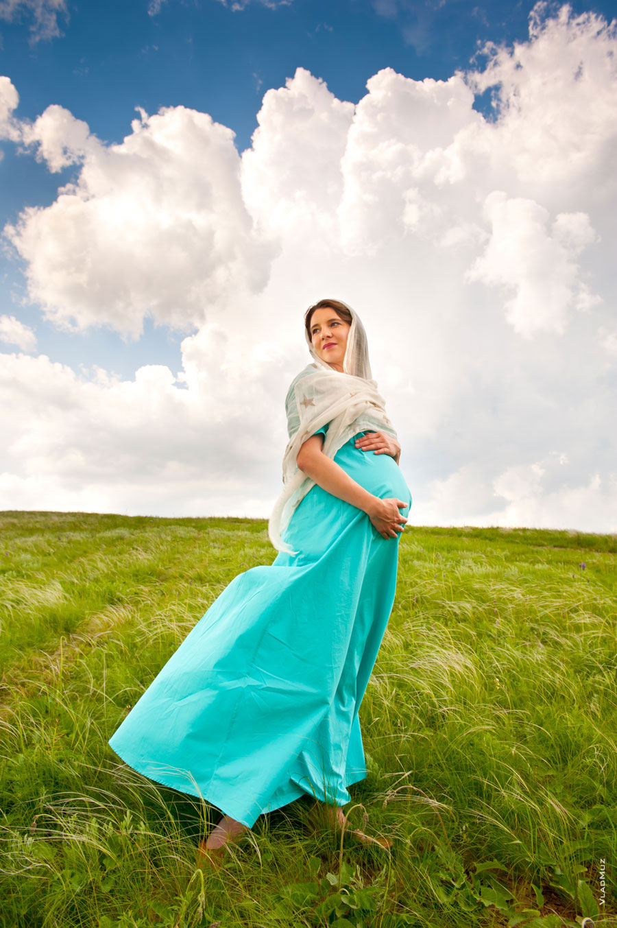 Фото беременной девушки в платье в белом платке на небесном фоне