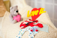 Детский фотонатюрморт: пинетки на фоне детской одежды и игрушек