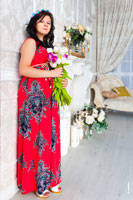 Фото беременной женщины в красном платье в полный рост в интерьере фотостудии
