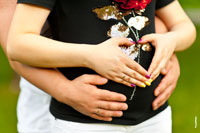 Фото мужских рук и женских ладоней в форме сердца на животе беременной
