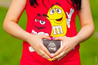 Фото беременной с фотоснимком УЗИ беременности на животе и с ладонями в форме сердца