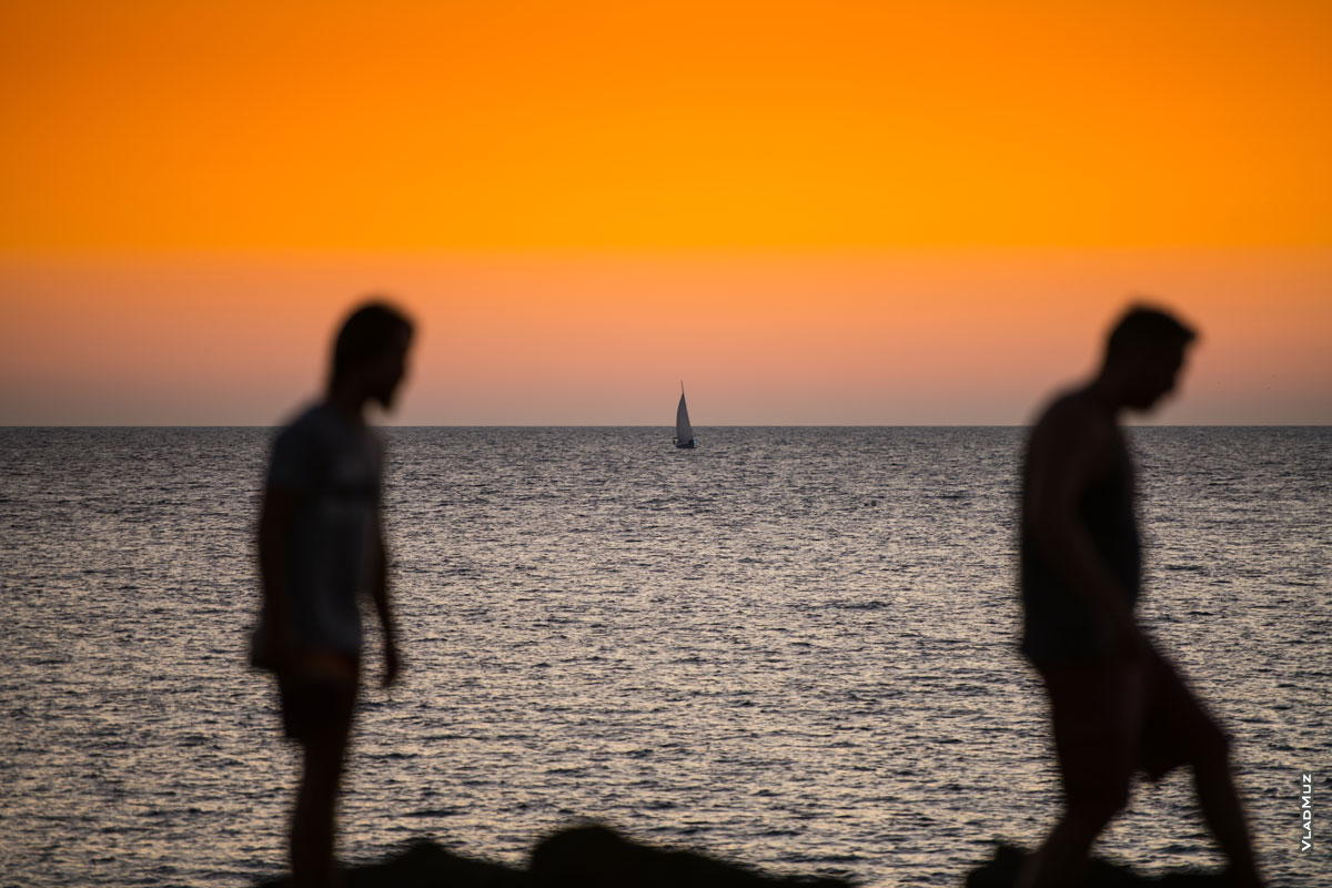 Жанровый фотопейзаж: фото яхты на морском горизонте, после заката солнца, на фоне 2-х силуэтов в расфокусе