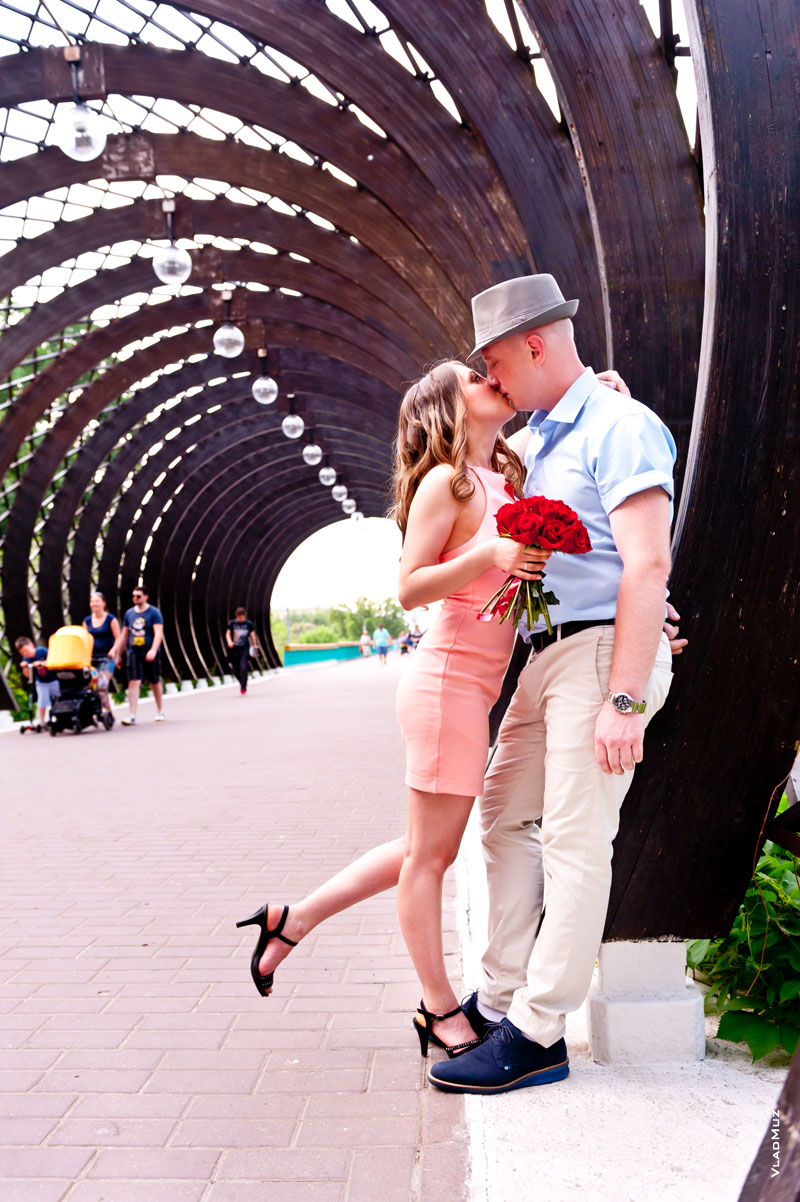 Фото поцелуя влюбленных, стоящих у сводчатых арочных пергол в парке Горького