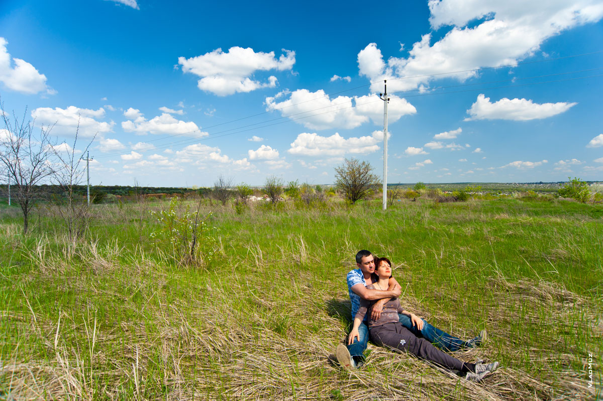 Фото влюбленных на траве, на фоне степных пейзажей, синего неба и облаков