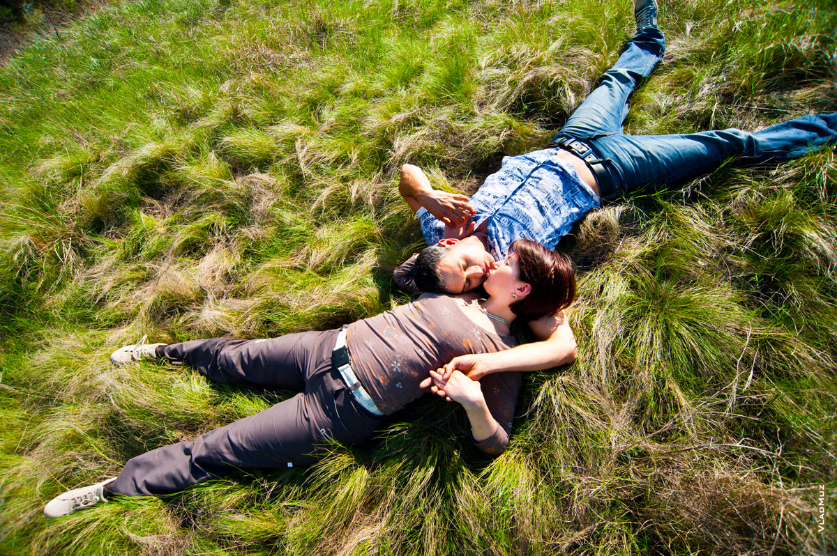 Фото поцелуя влюбленных, лежа на траве (вид сверху)