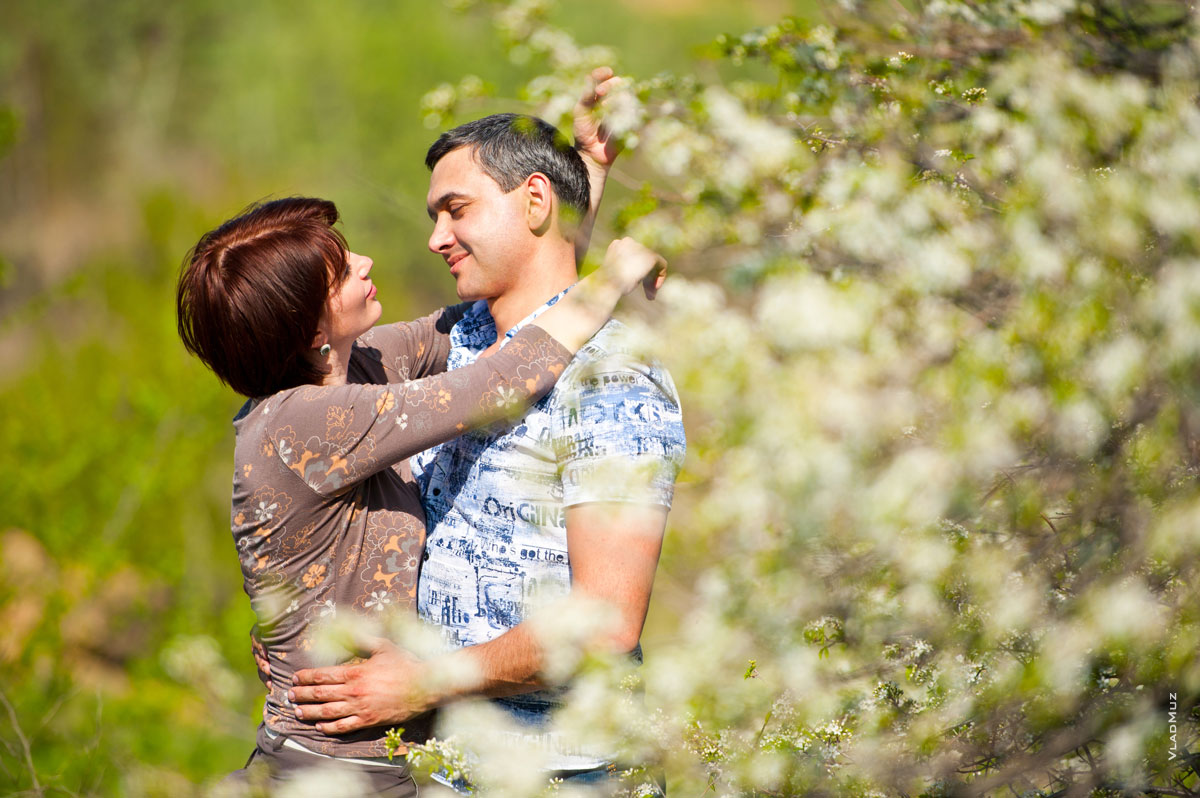 Романтическая фотография влюбленных в объятиях на фоне цветущих весенних деревьев
