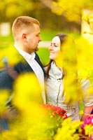 Фото мужчины и девушки рядом в расфокусе желтых цветущих ветвей деревьев