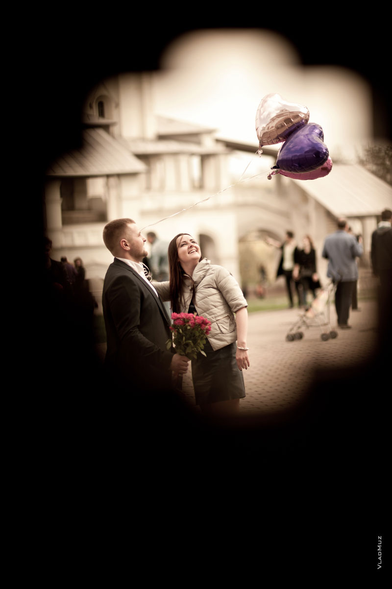 Фото влюбленной пары в проеме ворот и парящих над ними воздушных шаров