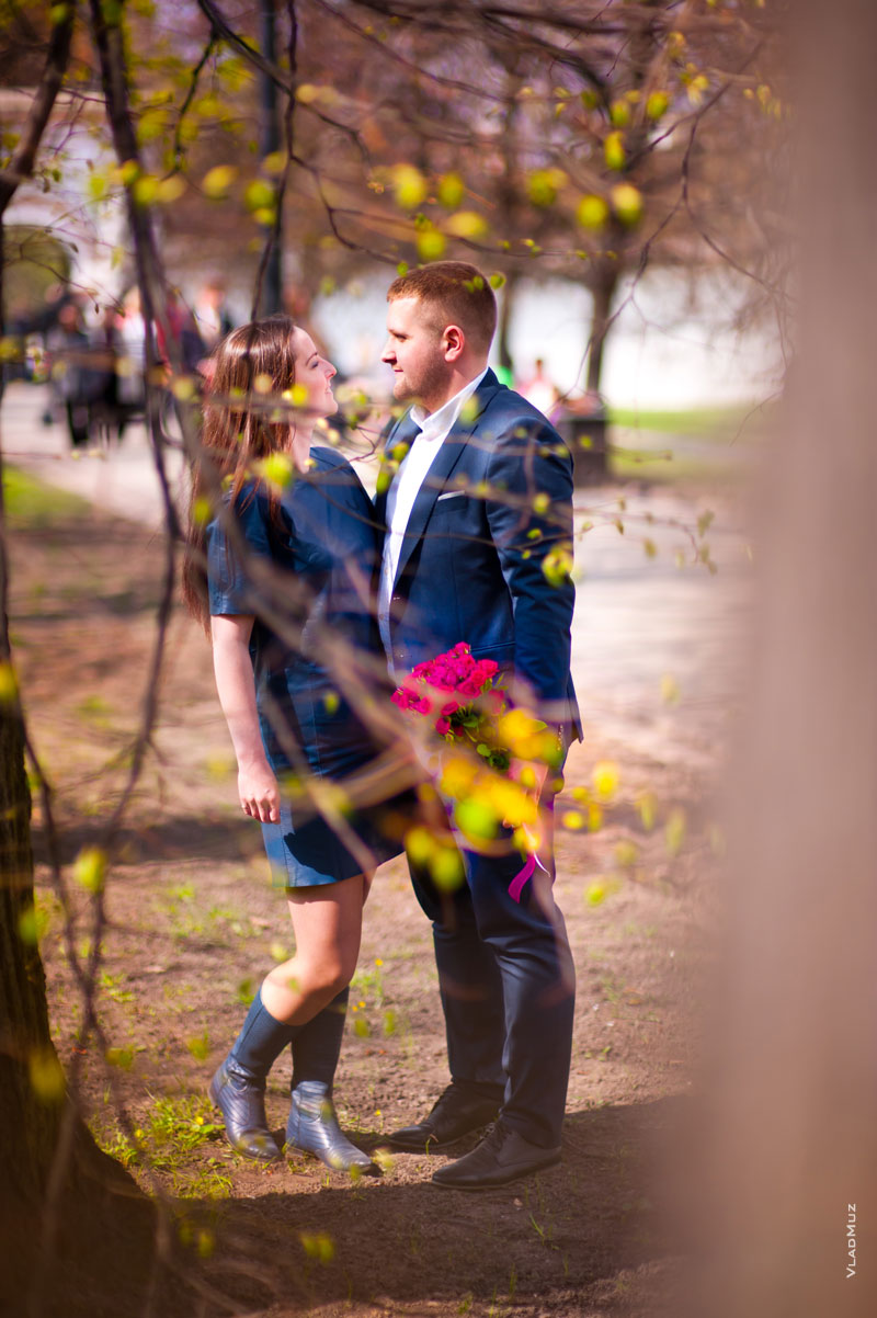 Фото девушки и мужчины рядом в расфокусе весенних цветущих ветвей