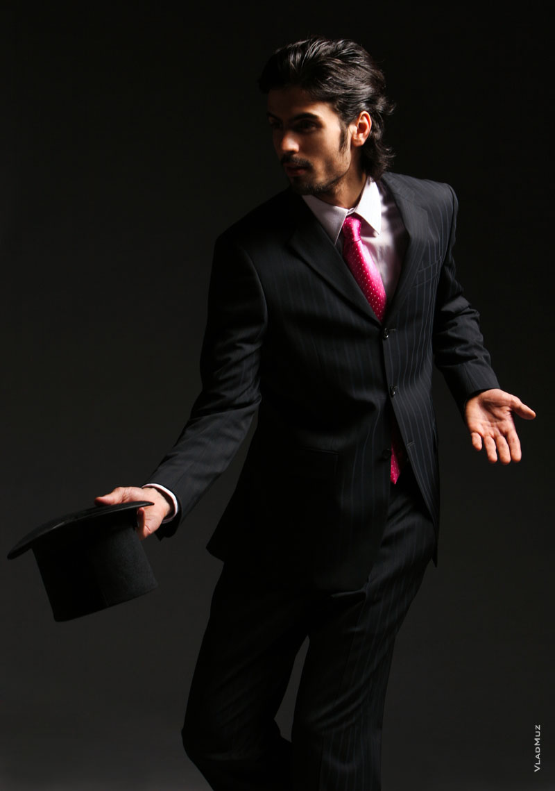 Динамичное фото мужчины в костюме с галстуком, с цилиндром в руке