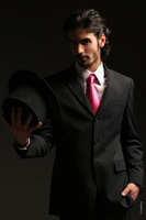 Фото красивого мужчины, профессиональной модели, в студии на темном фоне, с цилиндром в руке