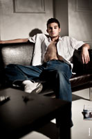 Фото мужчины в расстегнутой рубашке и джинсах, сидя на диване, в интерьере студии