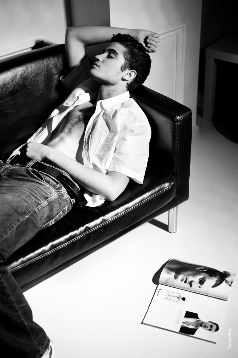Ч/б фото спящего на диване мужчины в рубашке и джинсах и мужской журнал рядом
