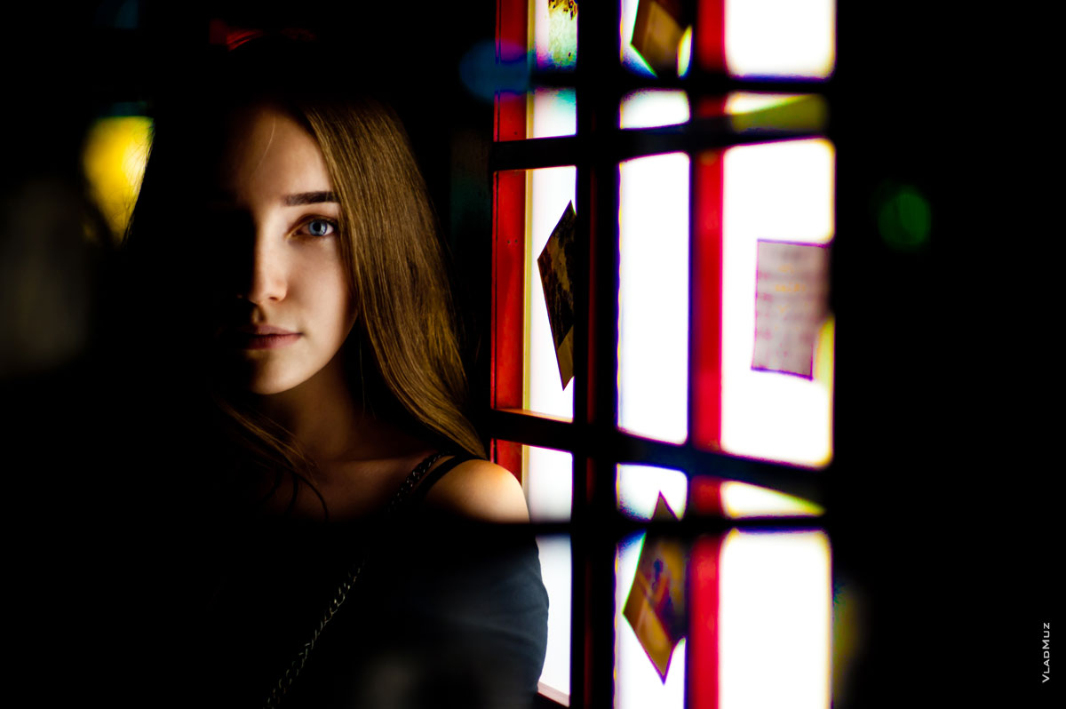 Фото девушки в расфокусе рамы и стекол двери телефонной будки