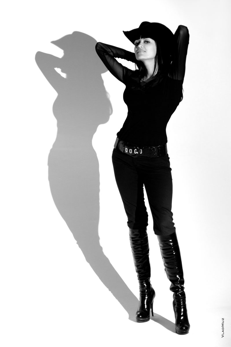 Модное модельное фото девушки и тени её фигуры на белой циклораме