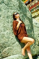 Фото девушки, облакотившейся на прибрежный камень