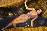 Вид сверху на девушку в купальнике, лежащей в прозрачной морской воде