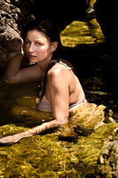Фото девушки в воде у каменистого морского берега
