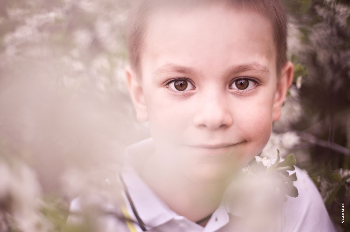 Детский весенний фотопортрет в цветущем саду с избирательной резкостью на глазах