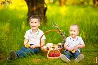 Фотопортрет детей в весеннем саду, на лужайке, с клубникой, пасхальными куличами и яйцами