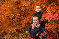 Фото портрет 2-х мальчиков осенью на фоне красно-желтых кустов скумпии