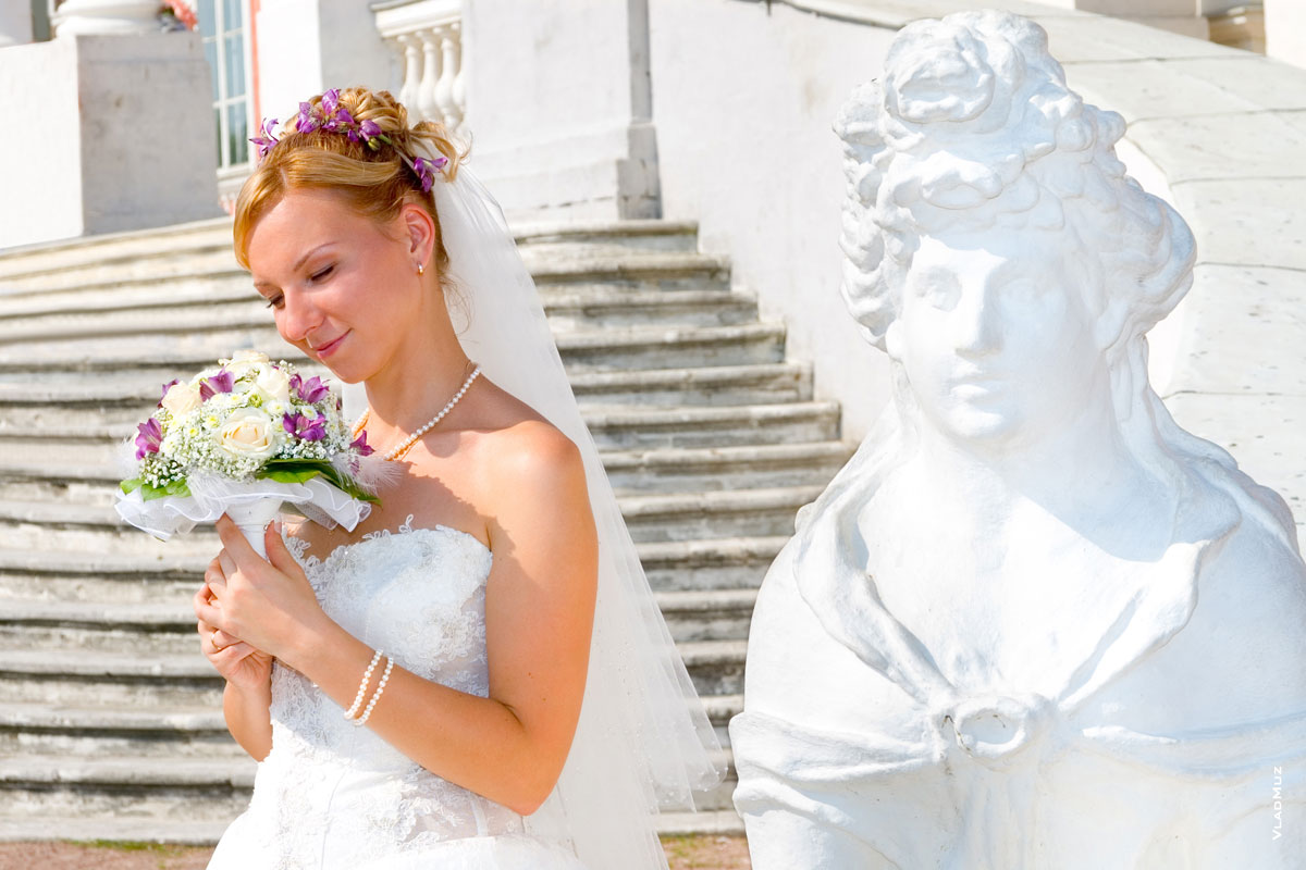 Жанровый фотопортрет невесты с букетом рядом со скульптурой женщины-сфинкса