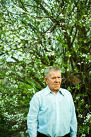 Жанровый фото портрет пожилого мужчины со строгим взглядом на фоне цветущего дерева
