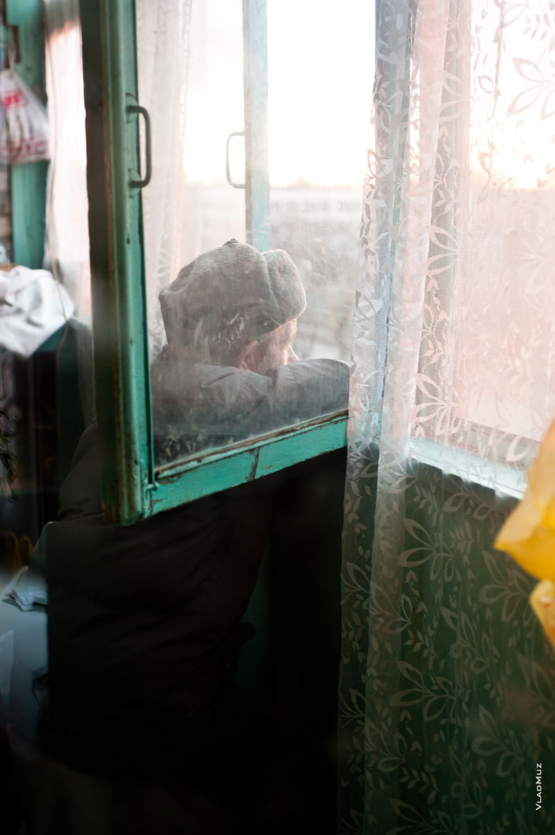 Жанровая фотография пожилого мужчины на балконе, смотрящего в окно