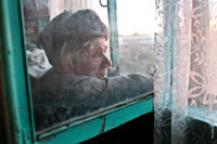 Жанровый портрет пожилого мужчины в шапке-ушанке у окна, фото сквозь грязное стекло